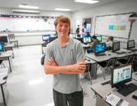  a young man crosses his arms in a computer lab